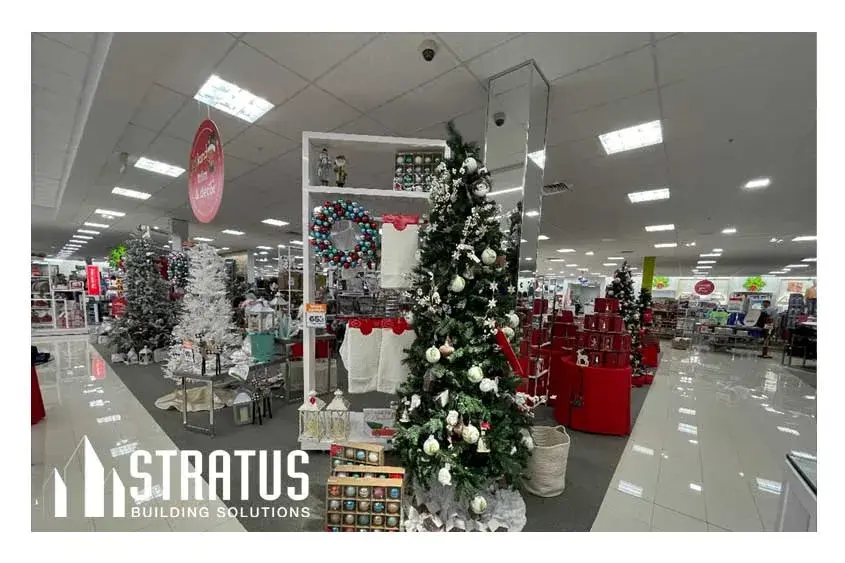 Interior of a retail store that is decorated for Christmas with several Christmas trees and ornaments.