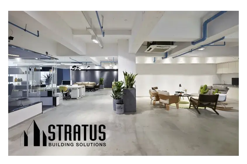 Open Modern Office with Concrete Floors, Cubicles on the Left, Sitting Area on the Right, and Potted Plants in the Middle